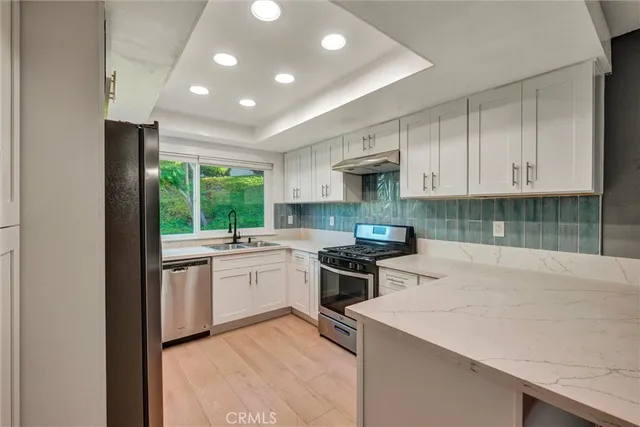 a kitchen with granite countertop white cabinets and stainless steel appliances