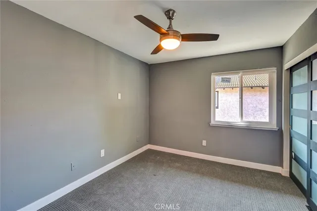 an empty room with closet and a chandelier fan