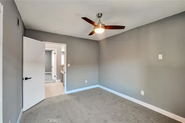an empty room with windows and ceiling fan