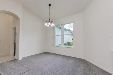 a view of an empty room with chandelier and window