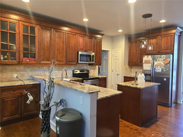 a kitchen with kitchen island granite countertop a sink appliances and cabinets
