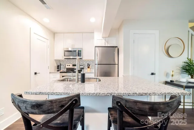a kitchen with granite countertop a table chairs stove and refrigerator
