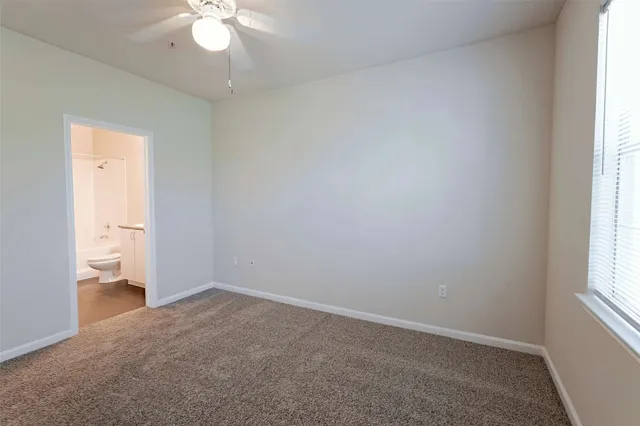 an empty room with a window and a ceiling fan