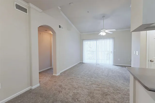 an empty room with windows and chandelier fan