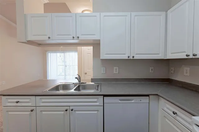 a kitchen with stainless steel appliances granite countertop white cabinets and a sink