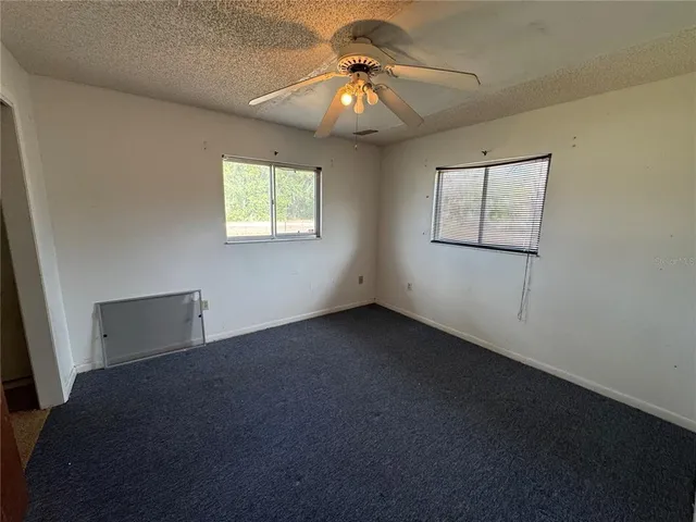a view of an empty room with window and chandelier fan
