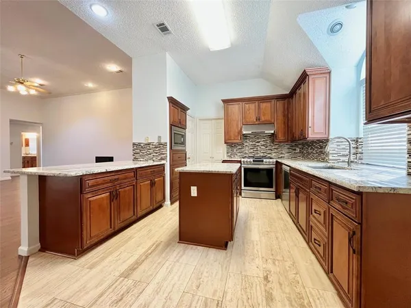 a large kitchen with stainless steel appliances granite countertop a stove a sink dishwasher and a refrigerator