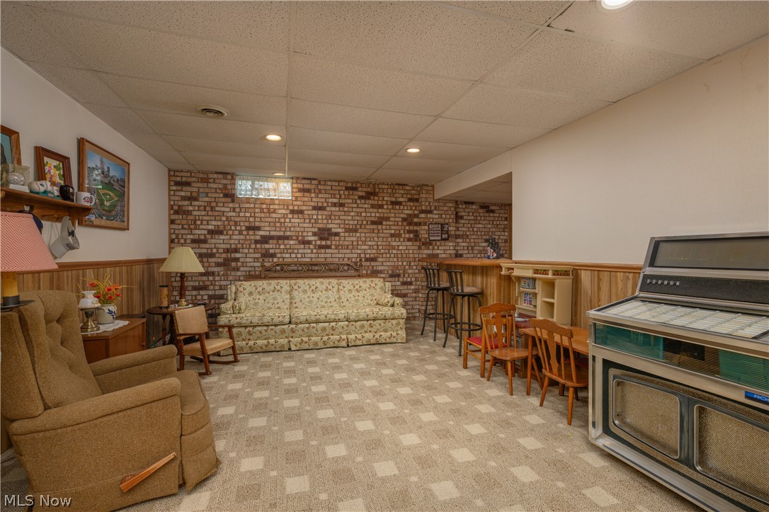 3281 Brenner Road Barberton, OH 44203 - Photo 31 of 33 Carpeted living room with brick wall, bar, and a paneled ceiling