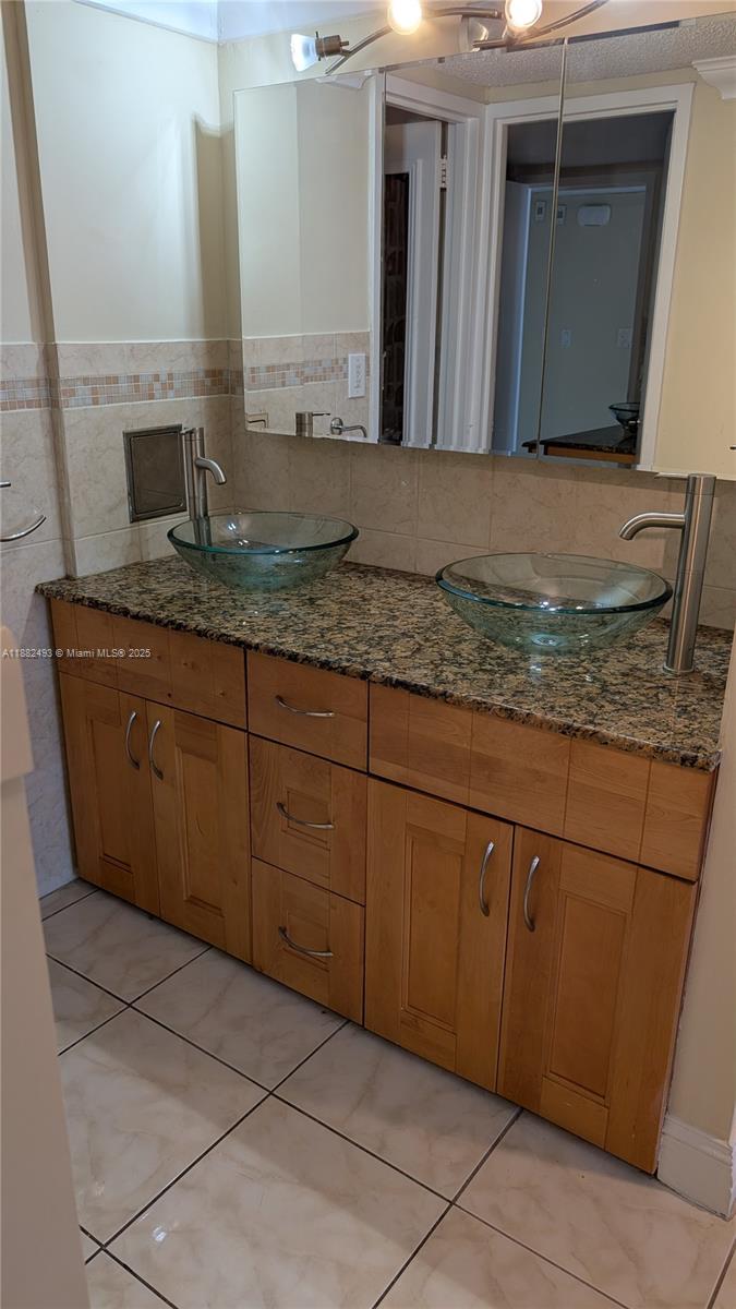 5701 Collins Avenue, Unit 1105 Miami Beach, FL 33140 - Photo 15 of 26 a bathroom with a granite countertop sink and a mirror