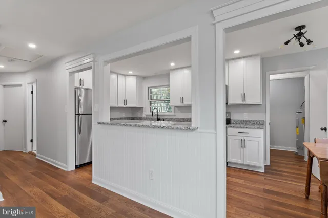 a kitchen with refrigerator a sink and wooden floor