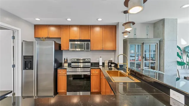 a kitchen with stainless steel appliances granite countertop a refrigerator a stove and a sink with wooden floor