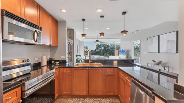 a kitchen with stainless steel appliances granite countertop a sink a stove and a wooden cabinets