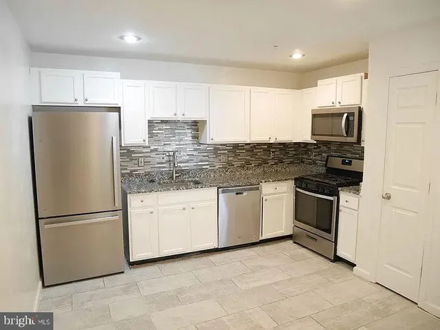 a kitchen with granite countertop a refrigerator sink and microwave