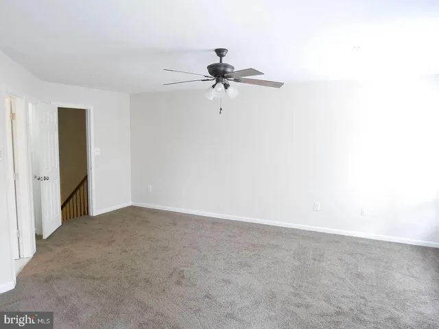 a view of a room with a ceiling fan and carpet