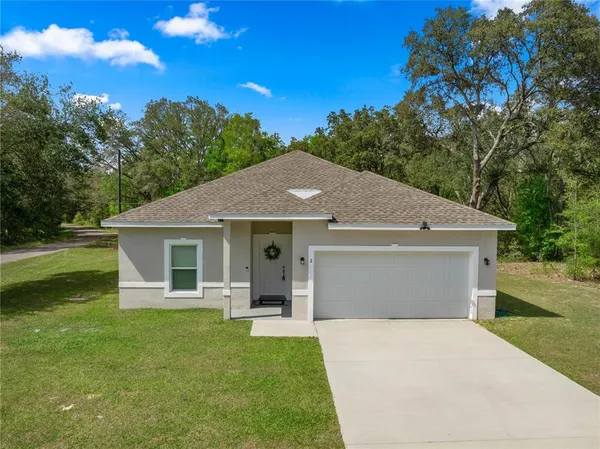 a front view of house with yard and trees in the background