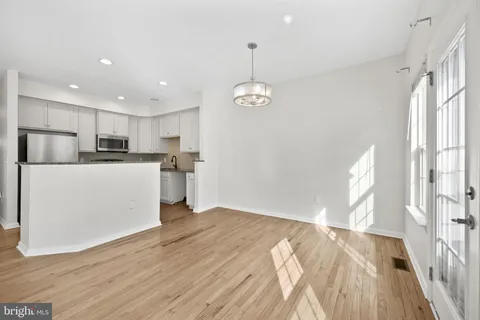 a kitchen with stainless steel appliances granite countertop a refrigerator a sink dishwasher a stove and white countertops with wooden floor