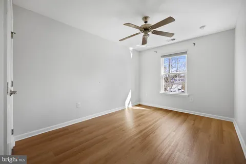 an empty room with wooden floor fan and windows
