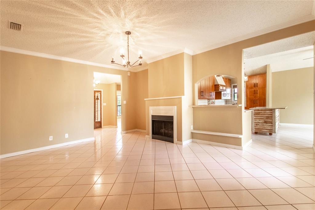 308 Sanders Road Denton, TX 76210 - Photo 13 of 31 Tile flooring throughout, a central chandelier, and a built-in fireplace with a mantel