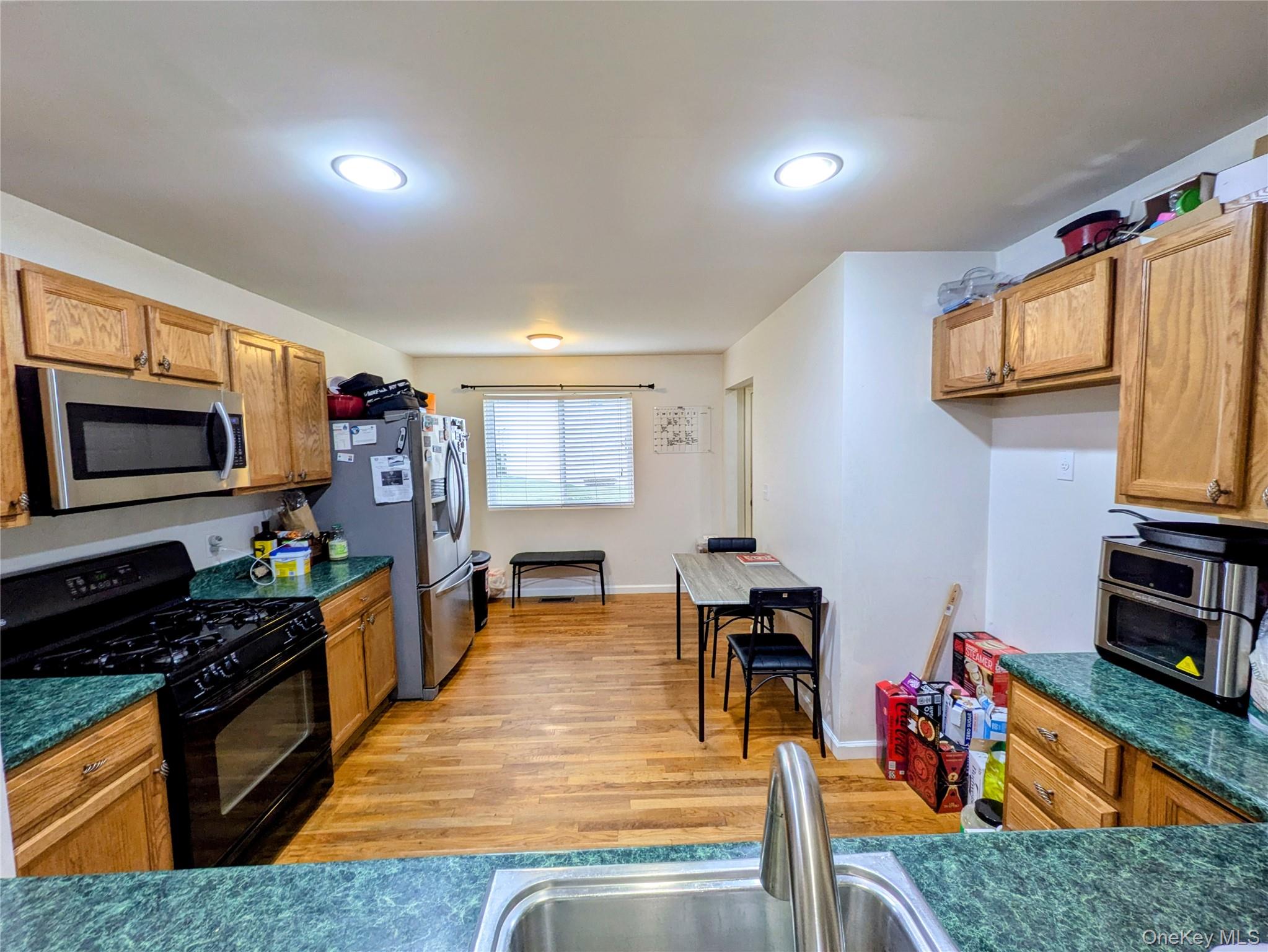 1206 Eagles Ridge Road Brewster, NY 10509 - Photo 10 of 29 Kitchen with appliances with stainless steel finishes, brown cabinets, light wood-style flooring, dark stone countertops, and recessed lighting
