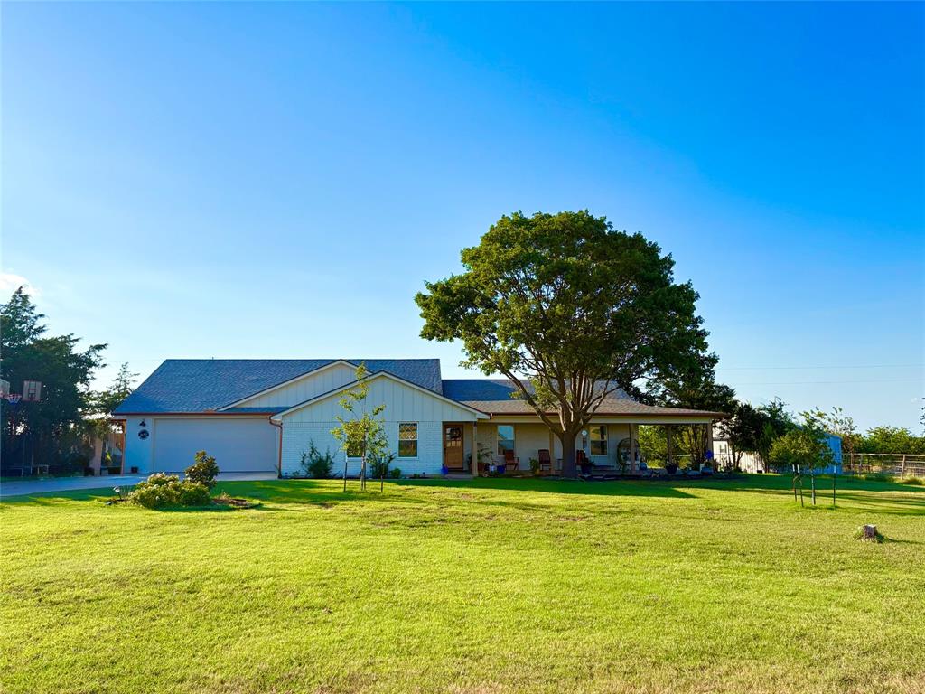 View of front facade with a front lawn, a garage, board and batten siding, and concrete driveway