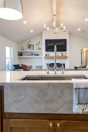 a living room with stainless steel appliances kitchen island granite countertop a sink and cabinets