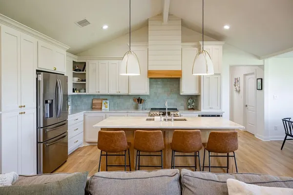 a kitchen with a dining table chairs refrigerator and microwave