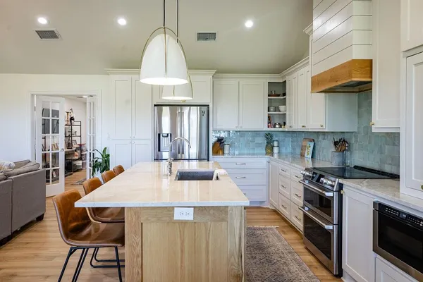 a kitchen with stainless steel appliances a stove a sink dishwasher a microwave oven and a dining table with wooden cabinet