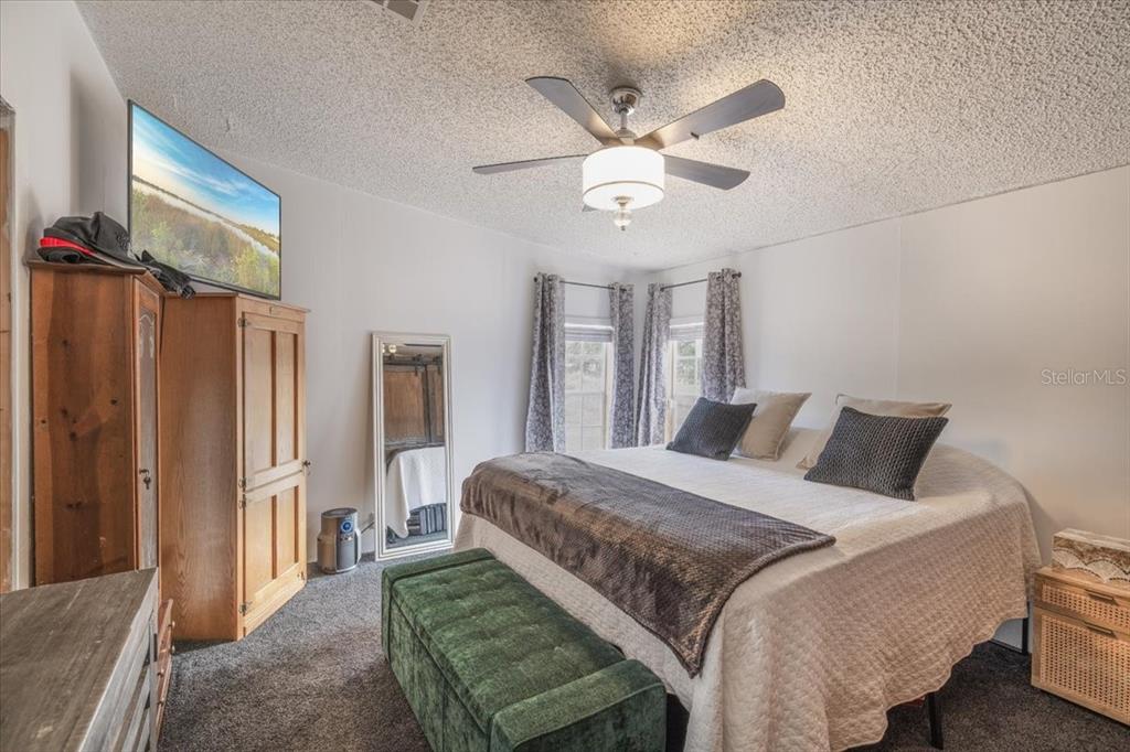 13205 Star Road Brooksville, FL 34613 - Photo 14 of 40 a bedroom with a large bed chandelier and a window