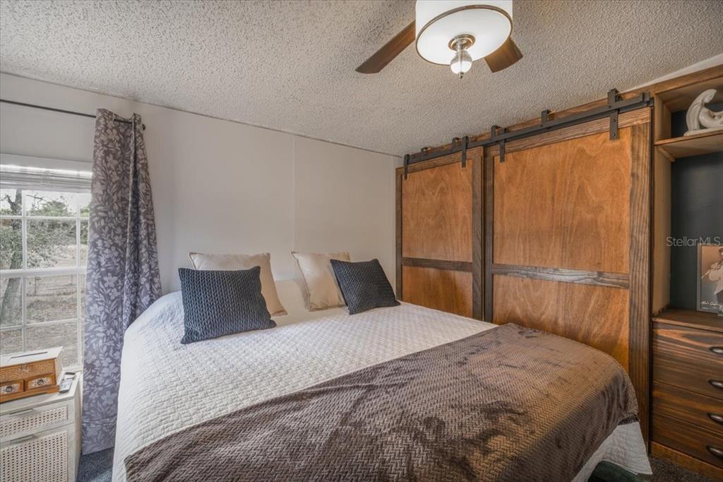 13205 Star Road Brooksville, FL 34613 - Photo 15 of 40 a bedroom with a large bed and a chandelier