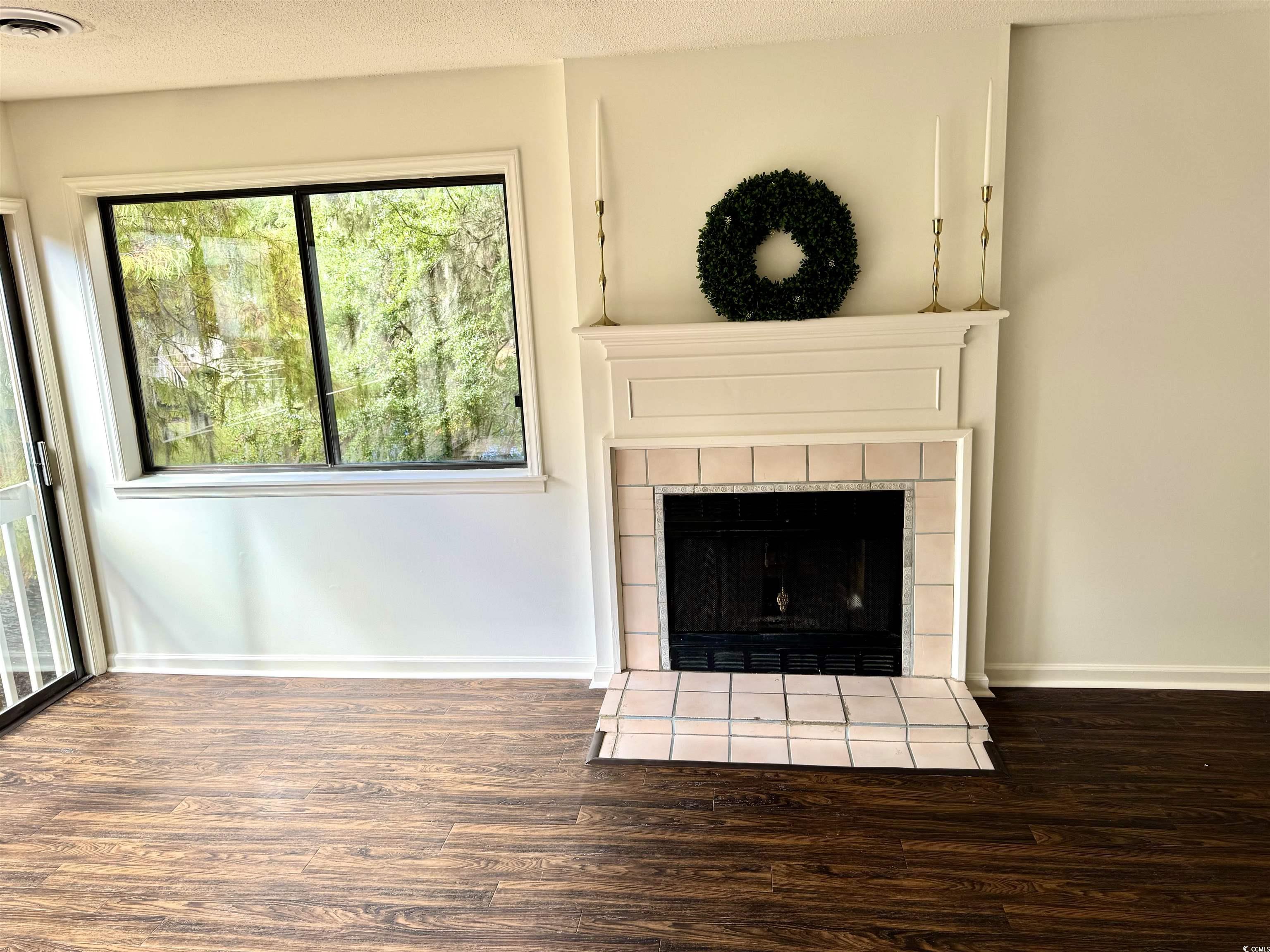 31 Battery White Court, Unit 1005 Georgetown, SC 29440 - Photo 3 of 34 Detailed view of a tile fireplace, wood finished floors, and a textured ceiling