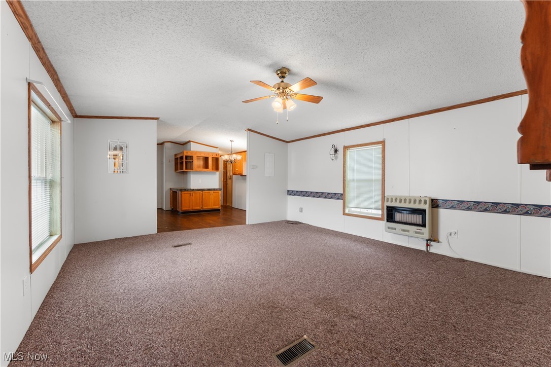 4455 Cleveland Road, Unit 6 Wooster, OH 44691 - Photo 5 of 40 Unfurnished living room with dark carpet, ceiling fan with notable chandelier, vaulted ceiling, a textured ceiling, and heating unit