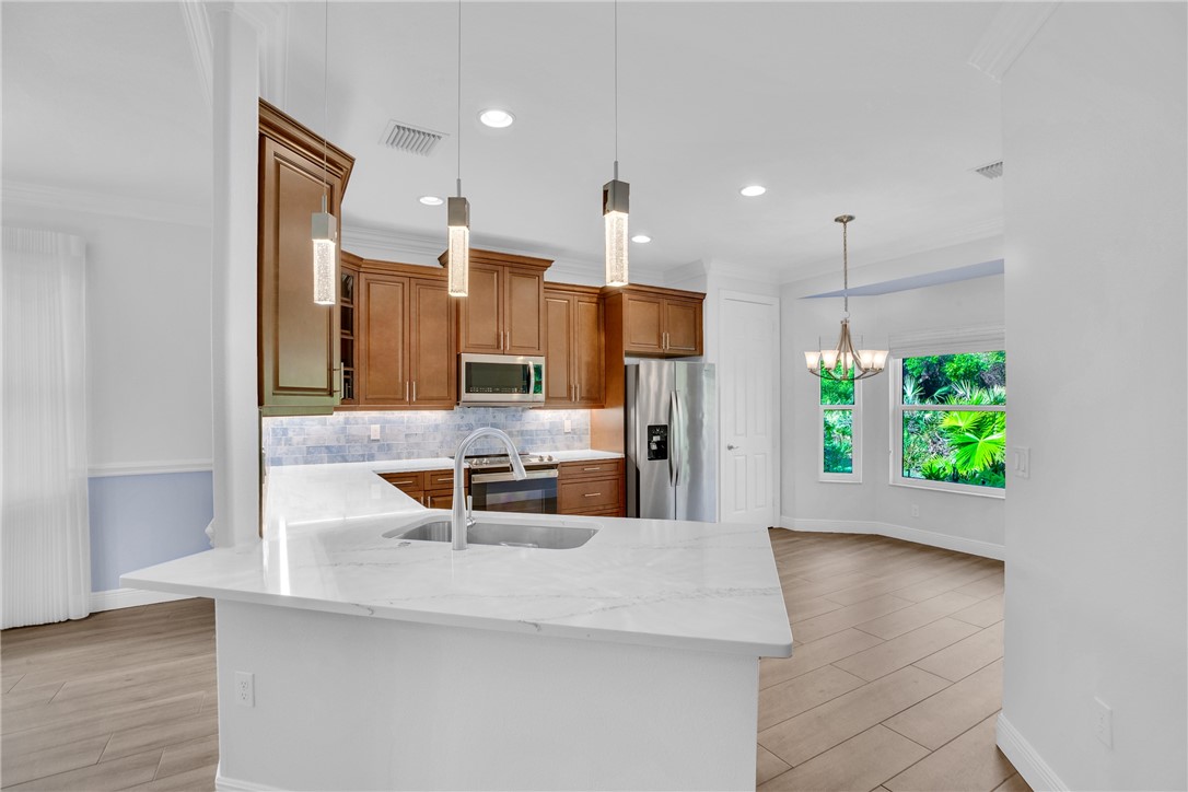 239 11th Square Southwest Vero Beach, FL 32962 - Photo 18 of 36 a kitchen with stainless steel appliances kitchen island granite countertop a refrigerator a stove and a wooden floors