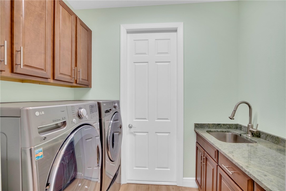 239 11th Square Southwest Vero Beach, FL 32962 - Photo 31 of 36 a utility room with stainless steel appliances granite countertop a sink and a washer dryer