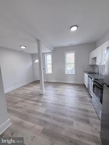 a view of kitchen and empty room with wooden floor