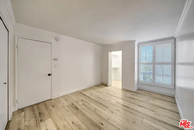 a view of an empty room with wooden floor and closet