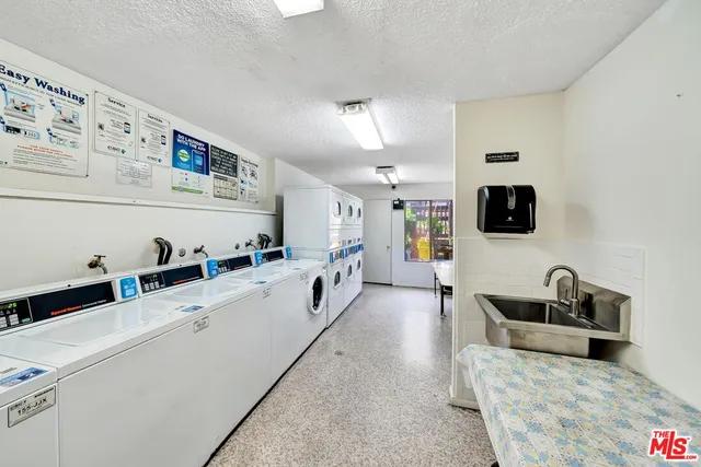 a view of a brick house with plants and large trees