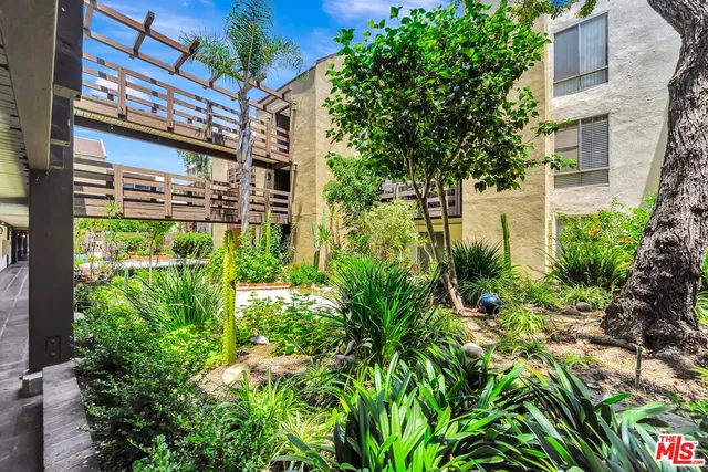 a view of a patio with couches chairs potted plants and wooden floor