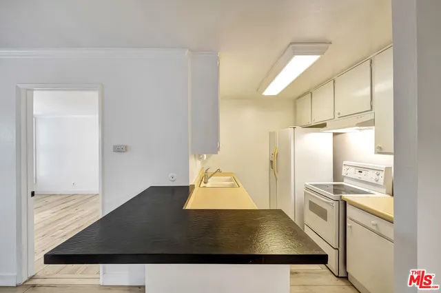 a kitchen with stainless steel appliances a refrigerator a stove and white cabinets