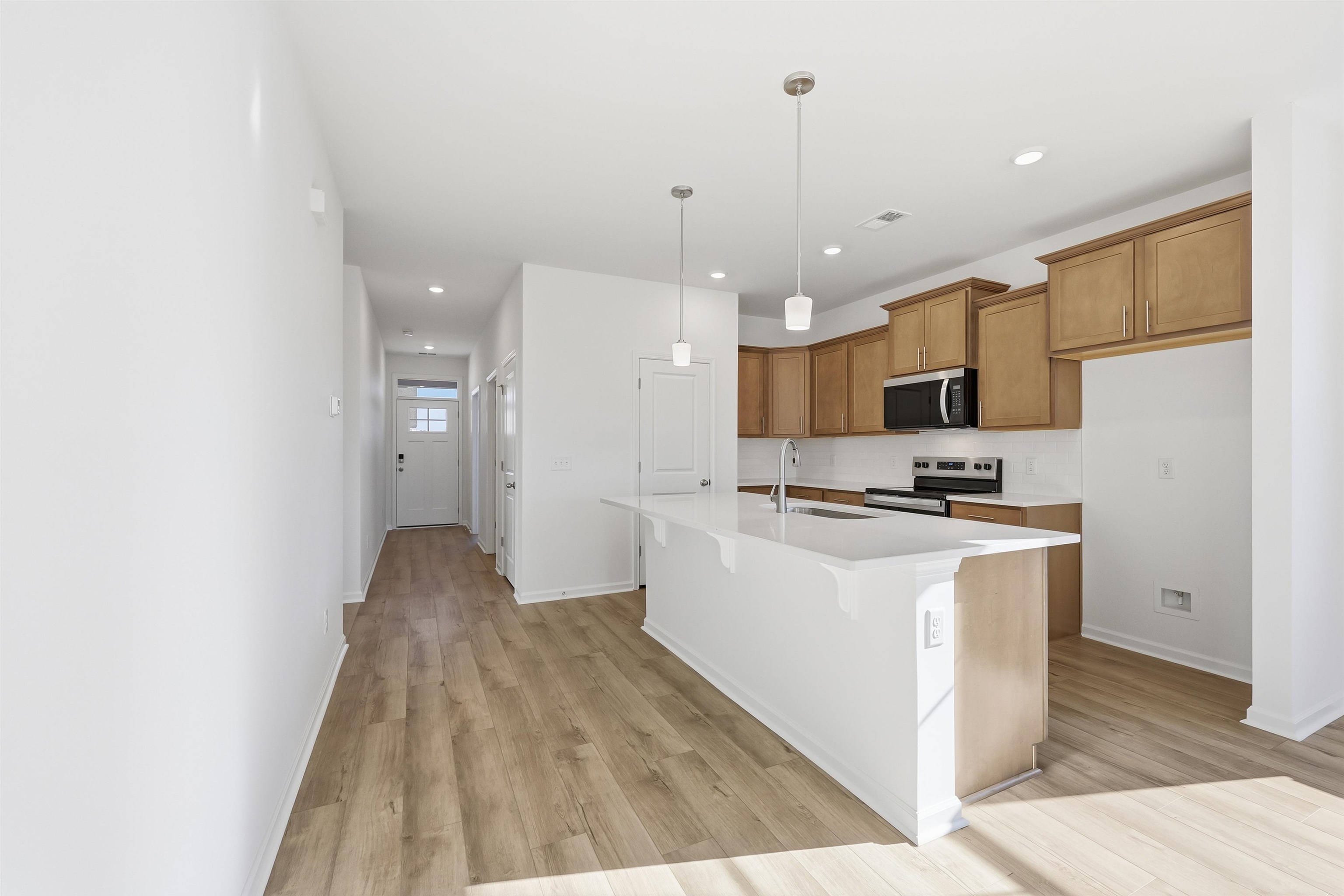 145 River Birch Drive Loris, SC 29569 - Photo 4 of 36 Kitchen featuring hanging light fixtures, brown cabinetry, an island with sink, a breakfast bar area, and appliances with stainless steel finishes