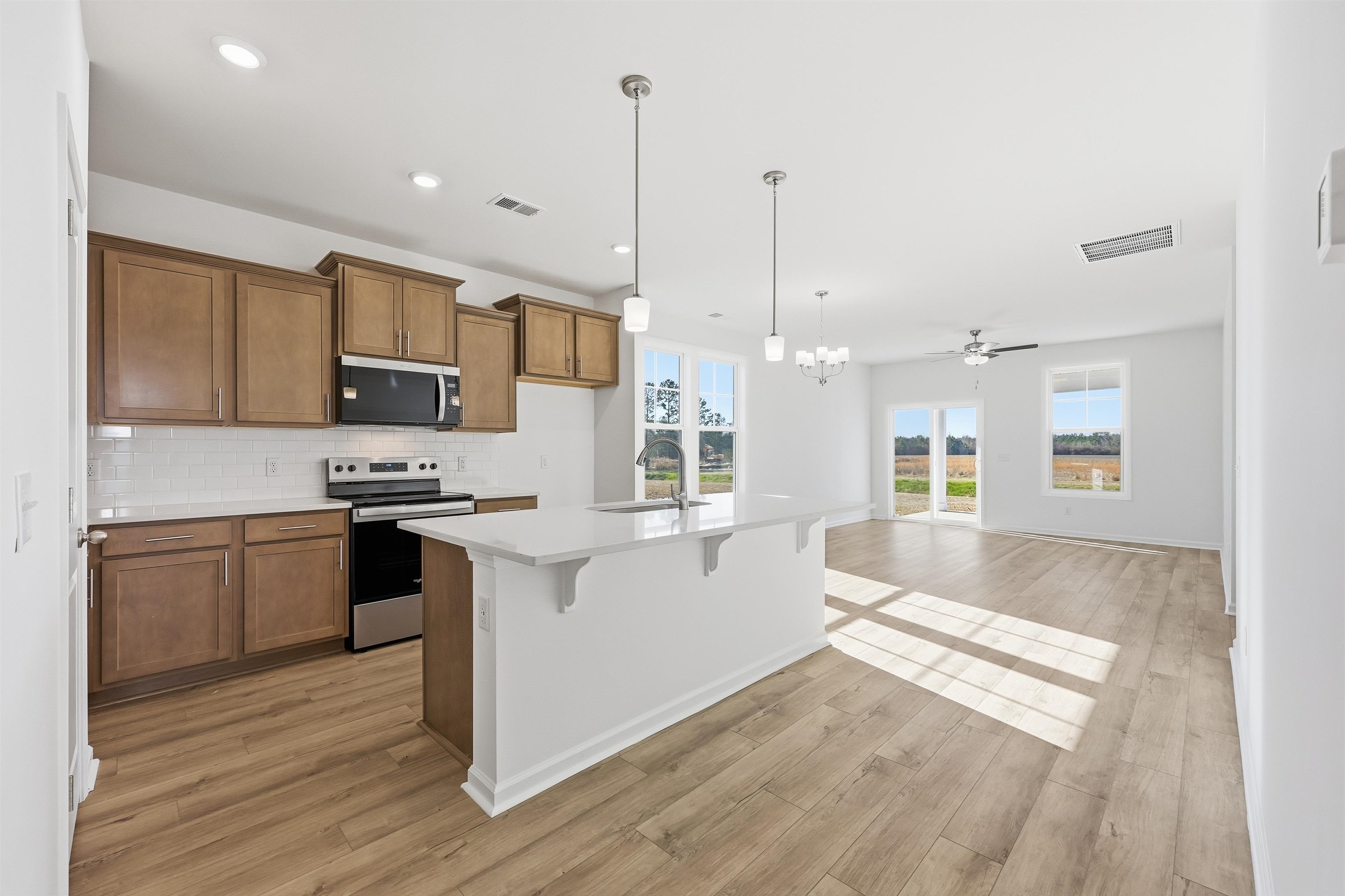 145 River Birch Drive Loris, SC 29569 - Photo 5 of 36 Kitchen with brown cabinetry, a kitchen breakfast bar, stainless steel appliances, pendant lighting, and a chandelier