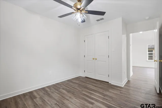 a view of a room with wooden floor and a ceiling fan
