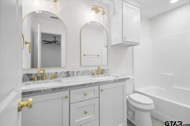 a bathroom with a granite countertop toilet sink and mirror
