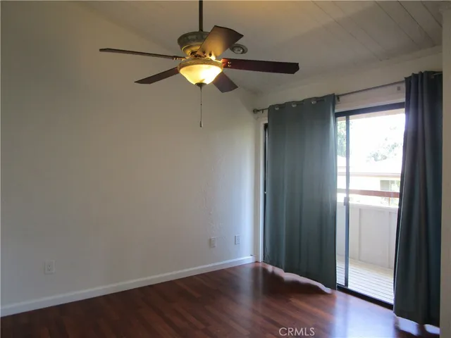 an empty room with wooden floor chandelier fan and window