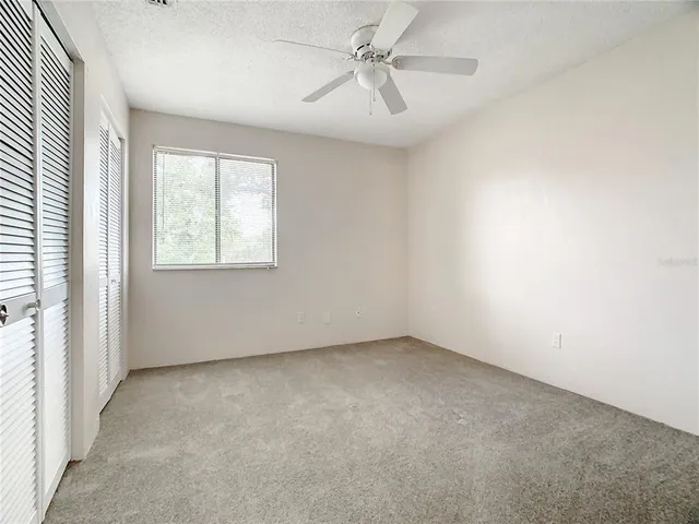 an empty room with windows and fan