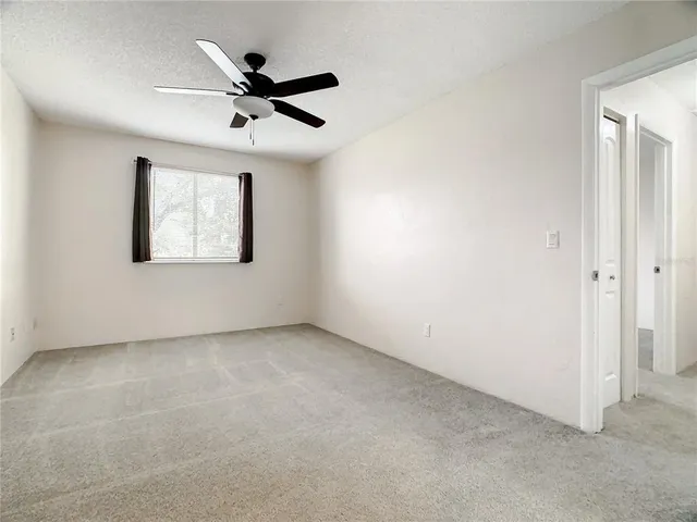 an empty room with ceiling fan and windows