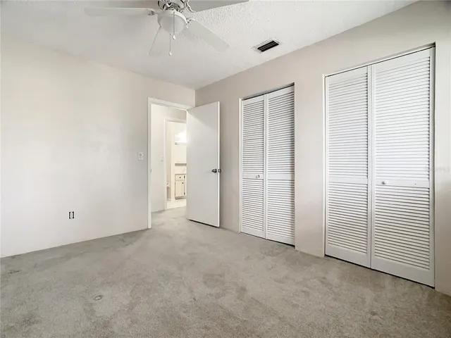an empty room with a ceiling fan and closet area