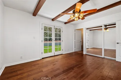 an empty room with wooden floor closet and windows