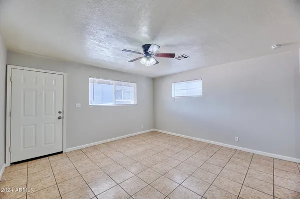 a view of an empty room and chandelier fan