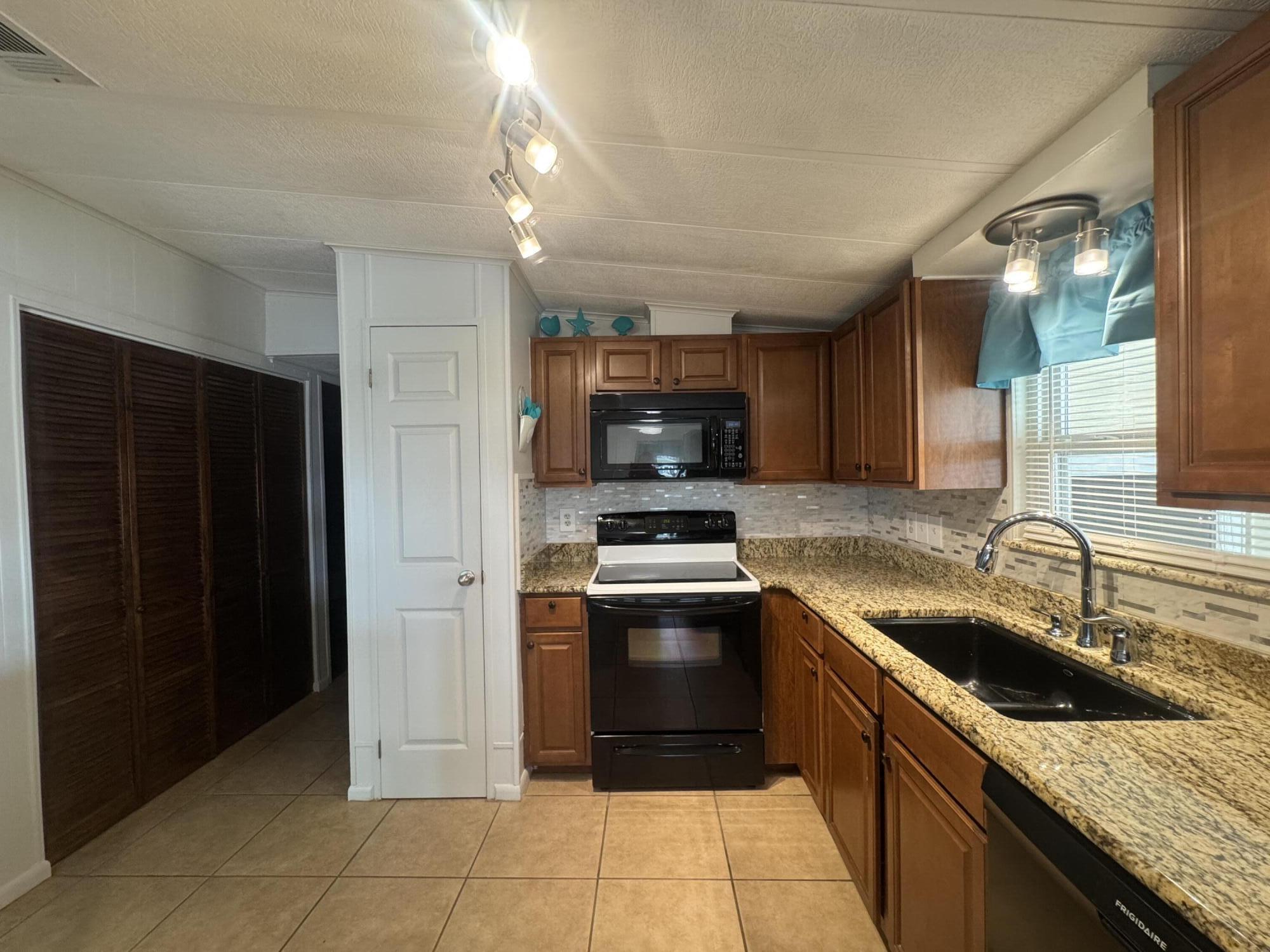 1747 Southwest 35th Circle Okeechobee, FL 34974 - Photo 8 of 21 a kitchen with stainless steel appliances granite countertop a sink and a refrigerator