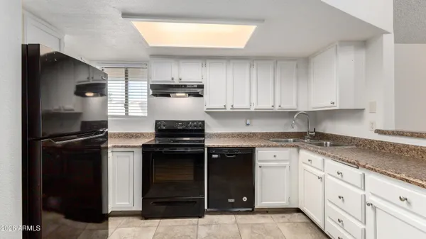 a kitchen with kitchen island granite countertop white cabinets and refrigerator